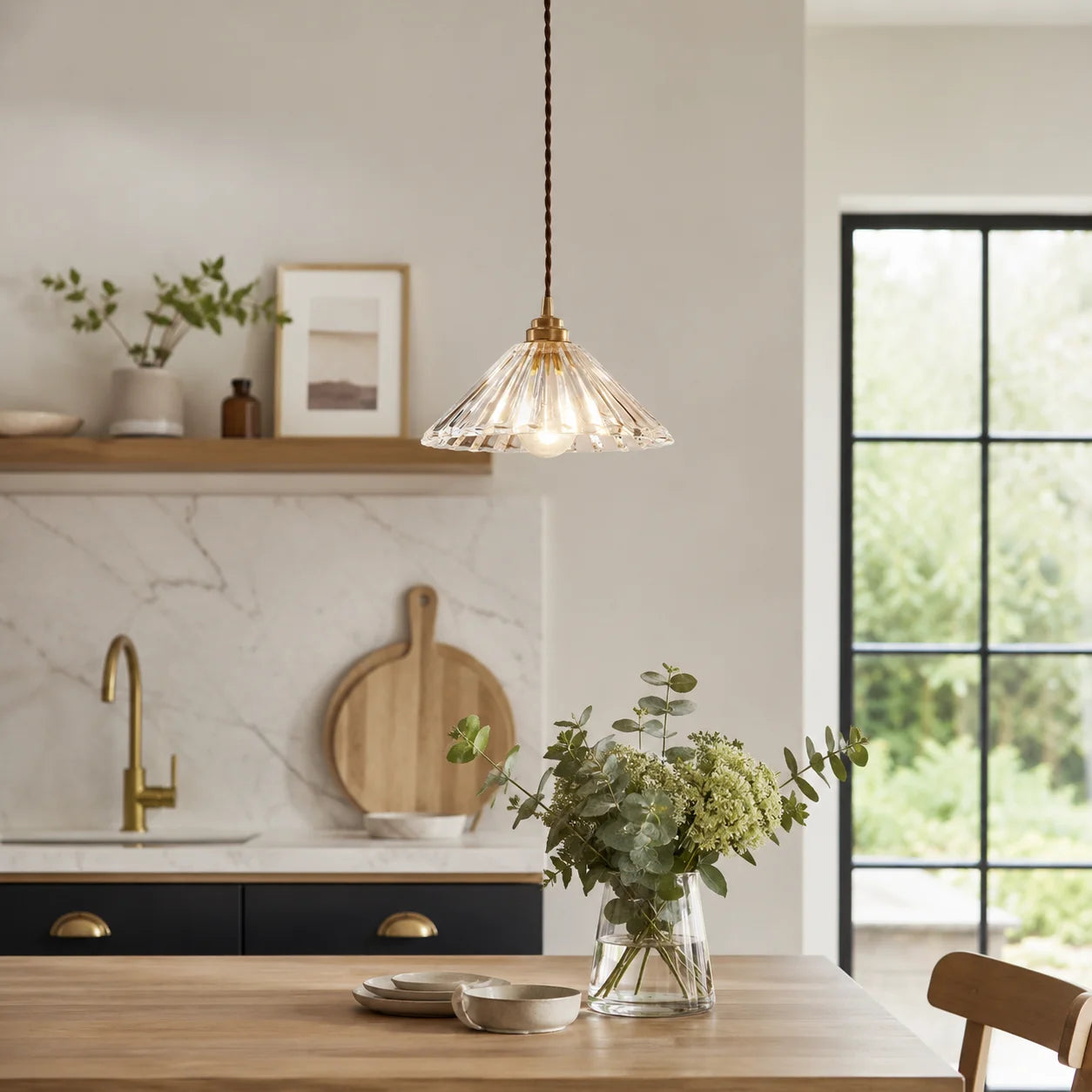 Modern glass pendant light with a ribbed shade and adjustable cord hanging above a wooden dining table in a stylish kitchen setting.