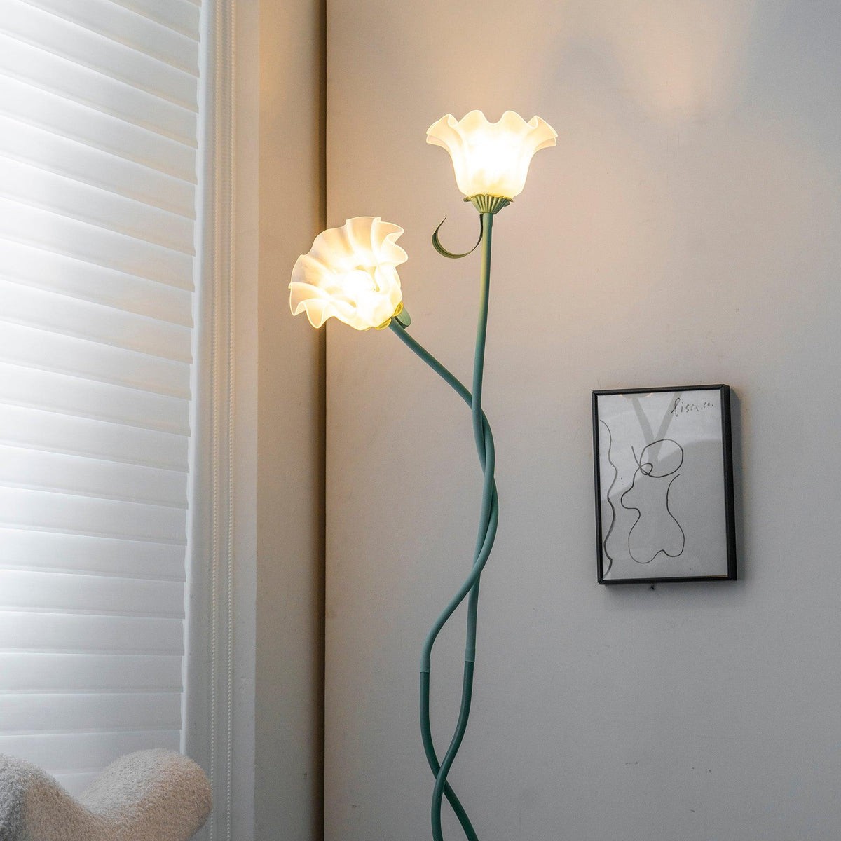 Two-head green flower lamp beside a framed print