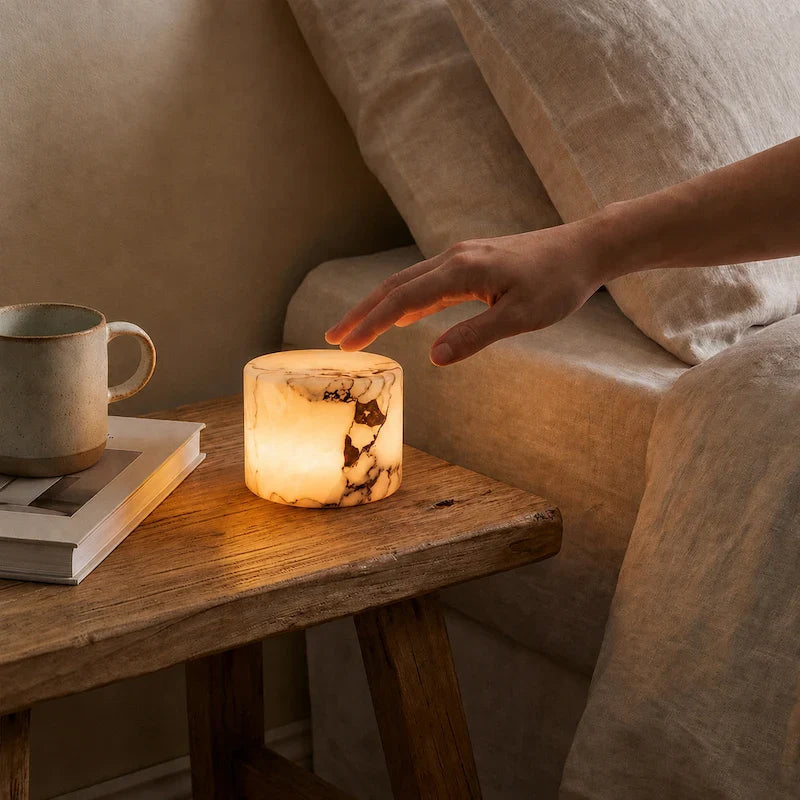 Hand reaching towards an illuminated marble table lamp