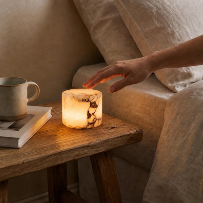 Hand reaching towards an illuminated marble table lamp