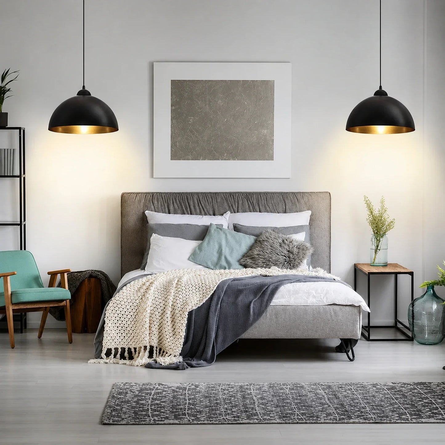 Two black and gold industrial dome pendant lights hanging above a modern grey upholstered bed in a stylishly decorated bedroom interior.