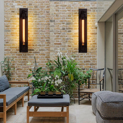 Two black industrial iron wall sconces with vintage filament bulbs mounted on a rustic brick wall in a stylish loft-style indoor living space.