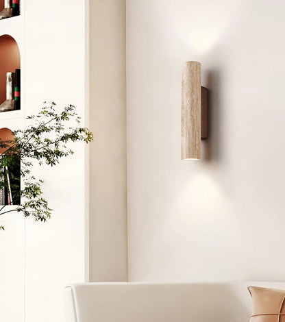 Travertine wall light with dark wood backplate above a console