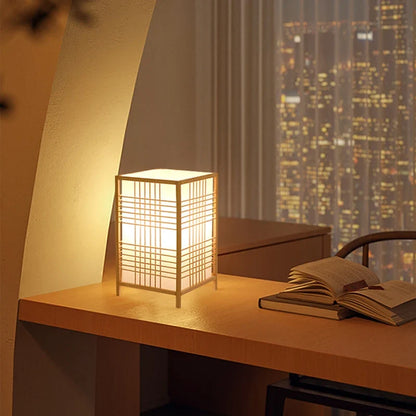 Japanese-style bamboo table lamp on a shelf beside books