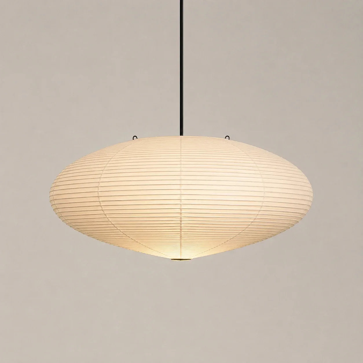 Minimalist Japanese oval rice paper pendant light measuring 45 by 25cm, featuring a warm glowing shade suspended from a slim black ceiling fixture.