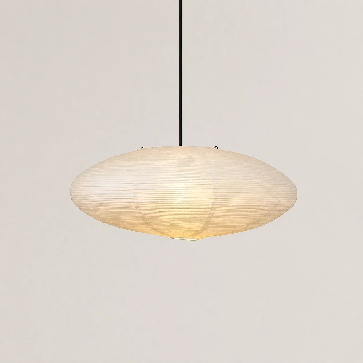 Japanese oval rice paper pendant light measuring 65 x 30cm, featuring a minimalist design with a warm glow, suspended by a slim black cord.