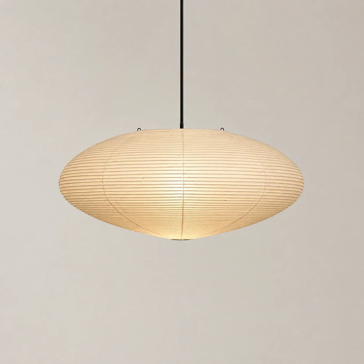 Minimalist Japanese oval pendant light featuring a textured cream rice paper shade suspended from a thin black cord against a neutral background.
