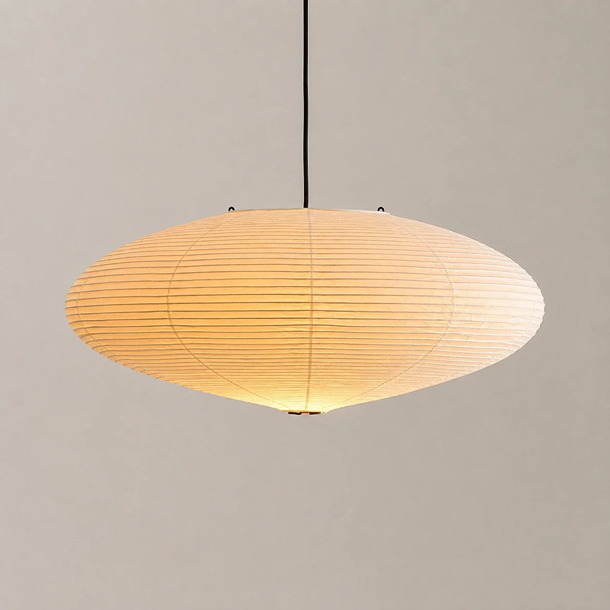 Minimalist oval rice paper pendant light with a warm glow, suspended by a black cord against a neutral background, perfect for Japandi interiors.