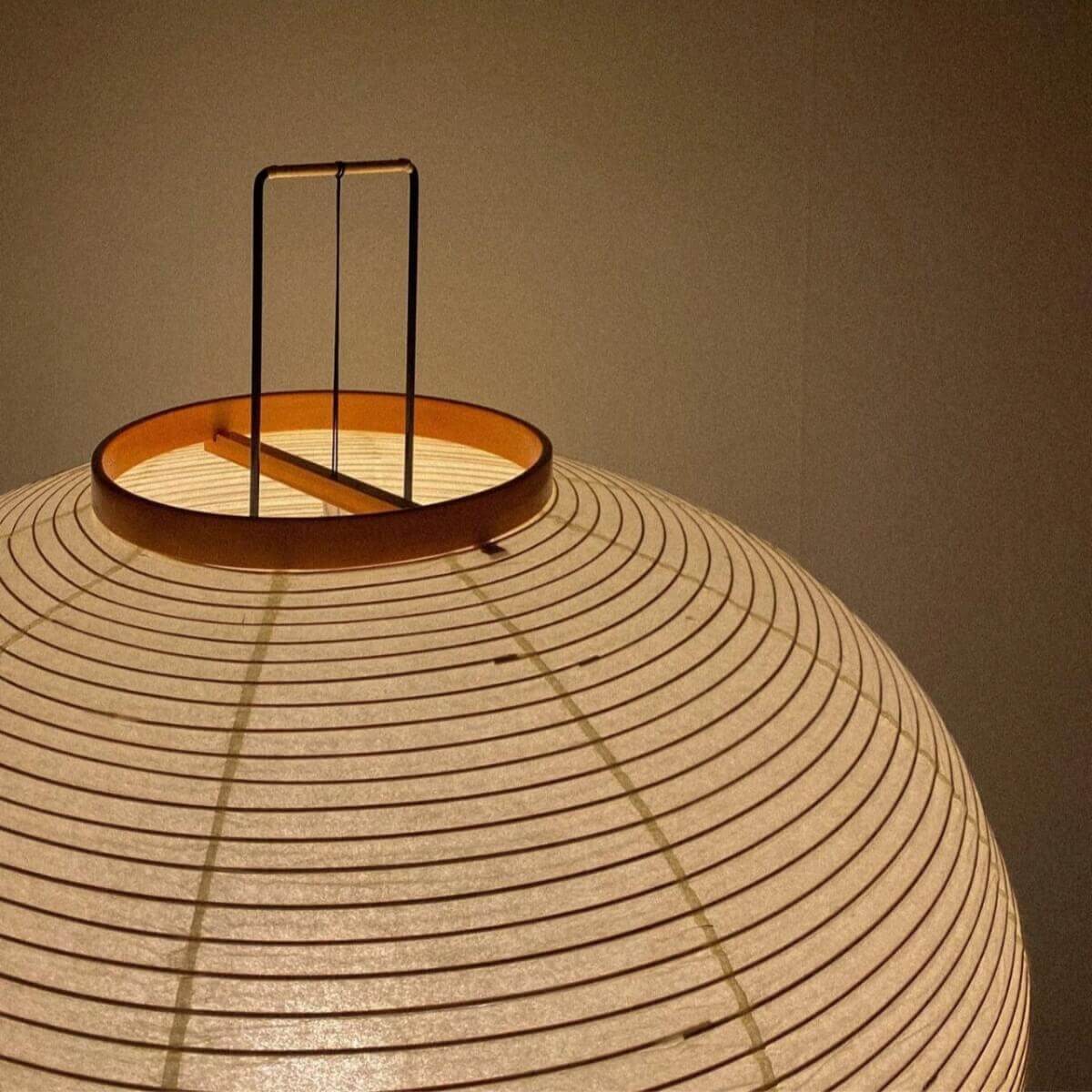 Close-up of a glowing Japanese rice paper floor lamp shade, showing its ribbed texture and warm, cosy light, perfect for bedroom or living room lighting.