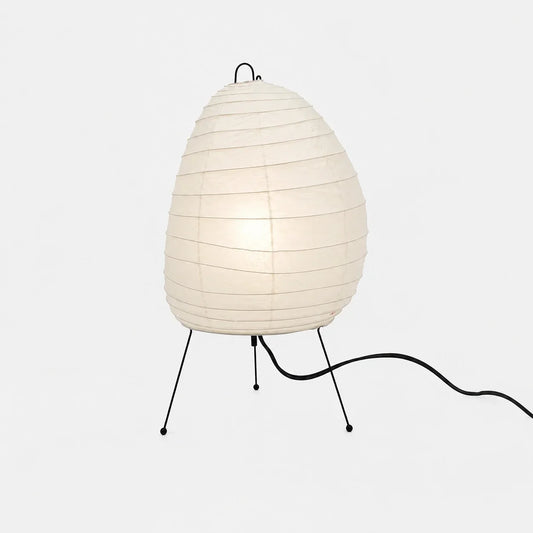 Japanese-style rice paper table lamp with an organic, egg-shaped shade supported by a slim black tripod stand, providing soft ambient bedroom lighting.