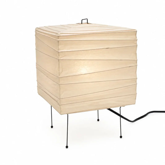 Minimalist square Japanese Washi paper table lamp with a cream shade, slim black metal legs and a small top handle, set against a plain white background.