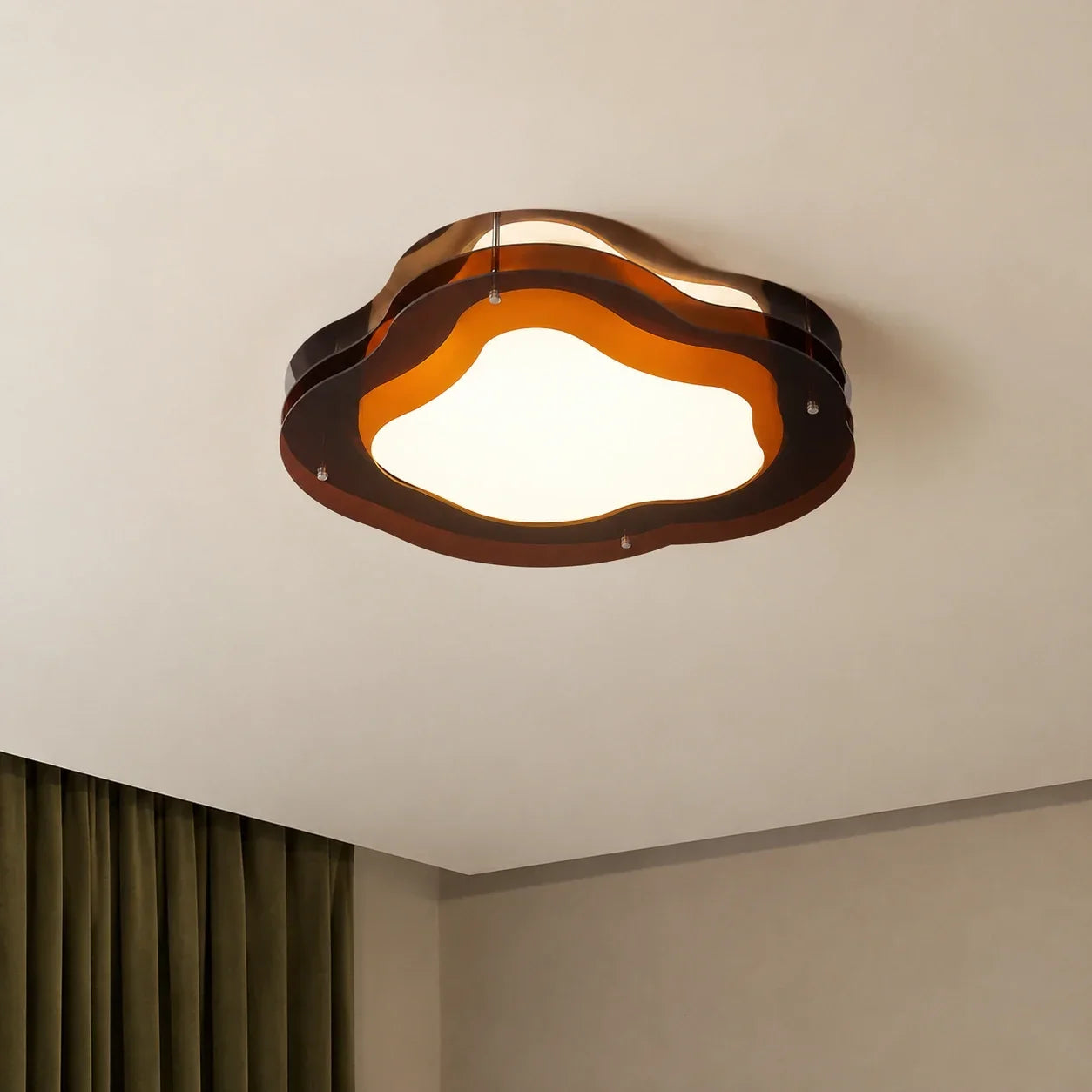 Modern cloud-shaped LED ceiling light with layered amber acrylic panels and a glowing white central diffuser, mounted on a neutral ceiling.