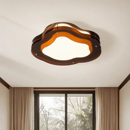 A modern cloud-shaped flush mount LED ceiling light with layered brown wavy panels, illuminated on a white ceiling in a contemporary room.