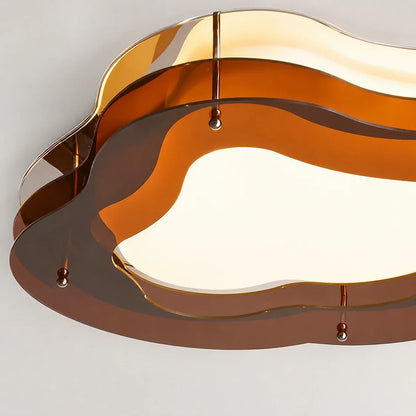 Close-up of a modern cloud-shaped flush mount ceiling light featuring layered, translucent amber and brown glass panels with a warm LED glow.