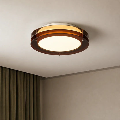 A modern round layered LED ceiling light featuring amber-coloured circular rings, emitting a warm, inviting glow on a neutral ceiling.