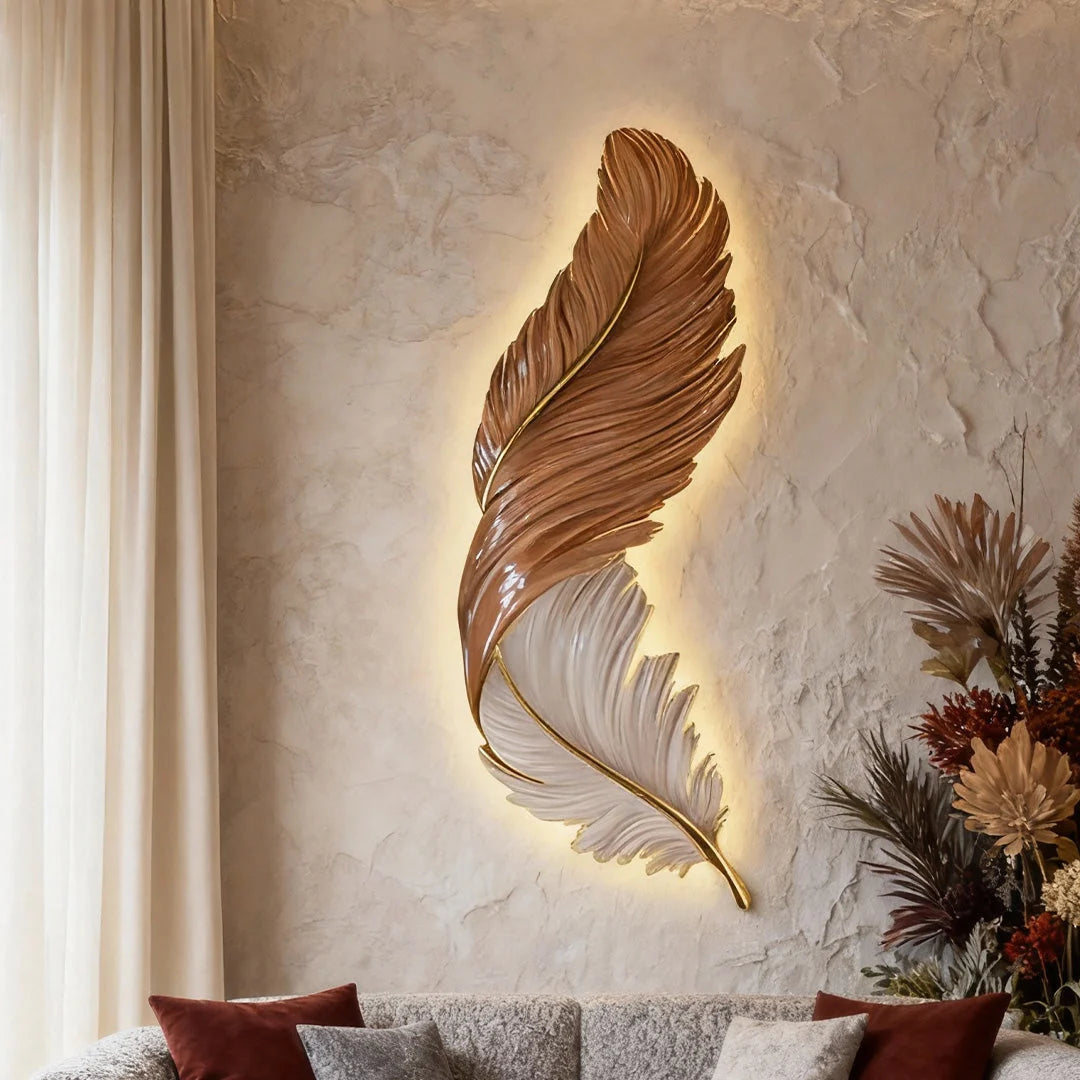 A modern feather-shaped LED wall lamp with a brown and white design, emitting a warm back-lit glow on a textured wall above a sofa.