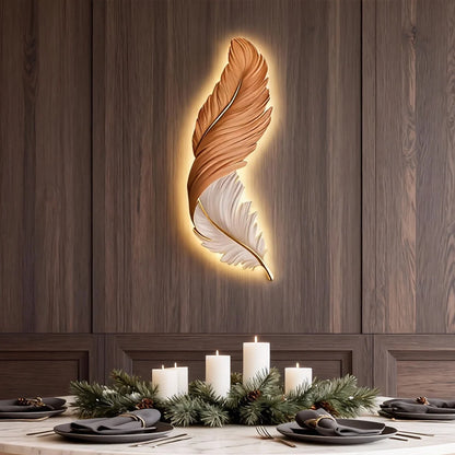 A modern feather-shaped LED wall lamp glowing with warm ambient light, mounted on a dark wood panelled wall above a festive dining table setting.