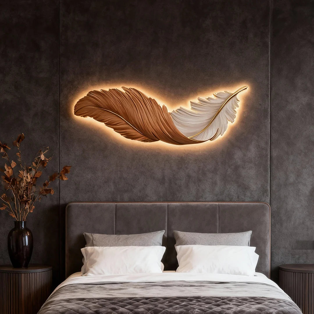 A modern LED feather wall lamp with warm backlighting mounted above a bed on a dark grey textured wall, creating a cosy bedroom ambience.