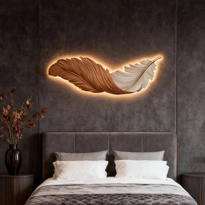 A modern LED feather wall lamp with warm backlighting mounted above a bed on a dark grey textured wall, creating a cosy bedroom ambience.