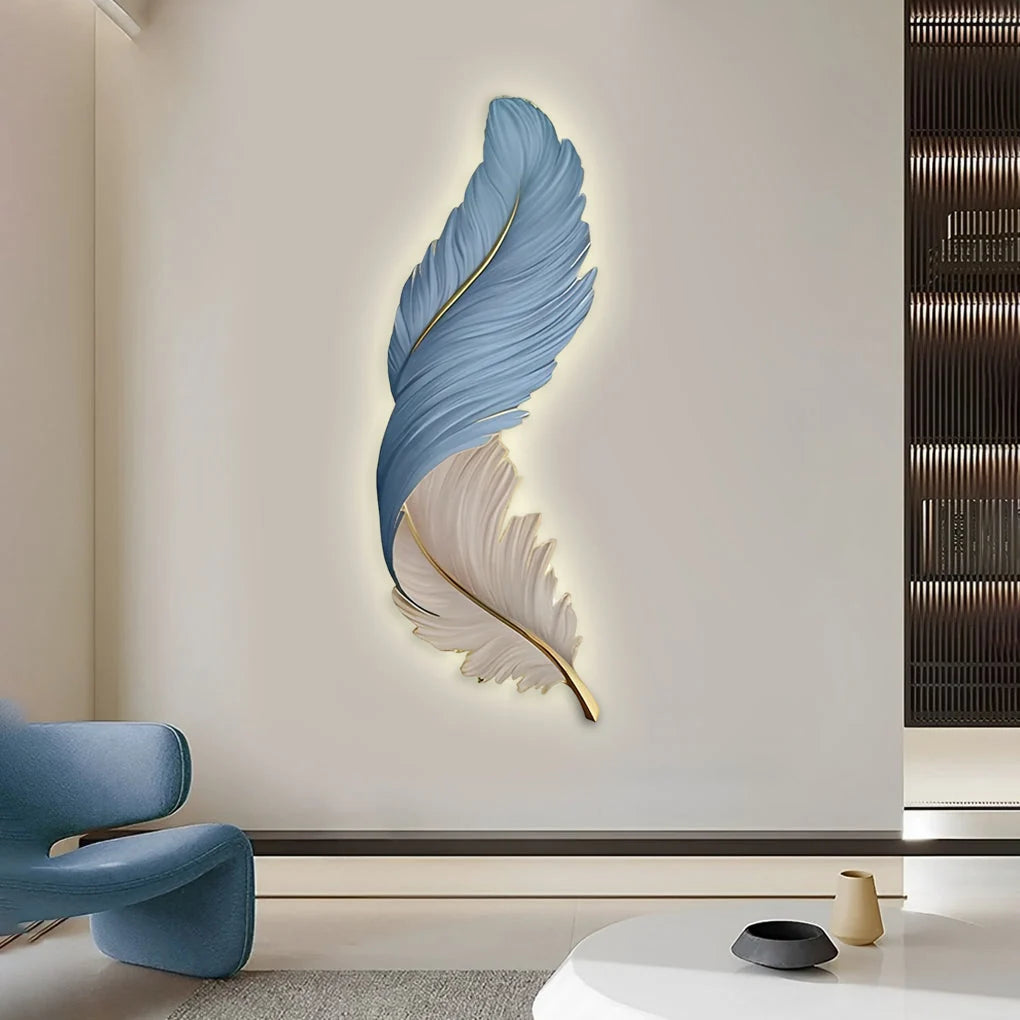 A vertical blue and white feather-shaped LED wall lamp mounted on a modern living room wall, providing soft ambient lighting with a gold-toned accent.
