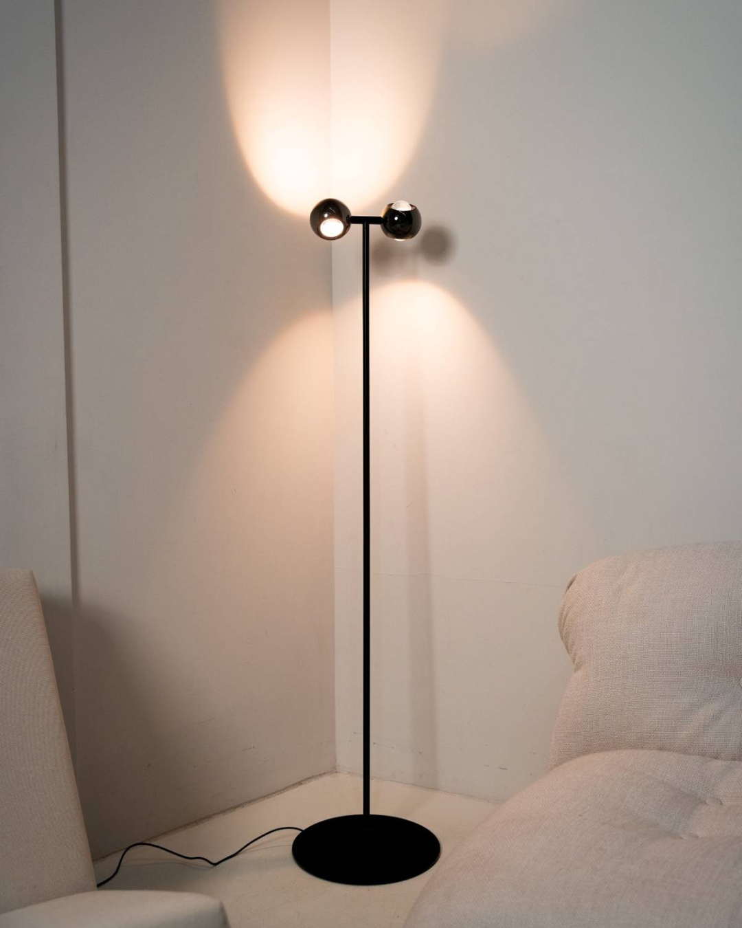 Twin-head floor lamp projecting light onto a wall