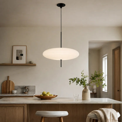 A minimalist white flying saucer LED pendant light hanging above a kitchen island with a marble countertop in a modern Nordic-style kitchen.