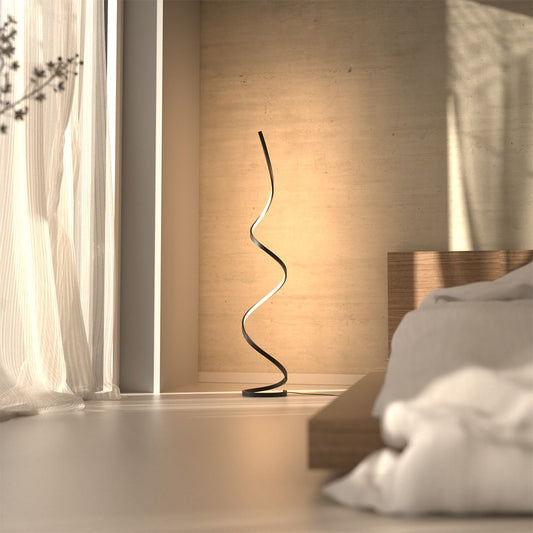 Black LED spiral floor lamp beside a bed