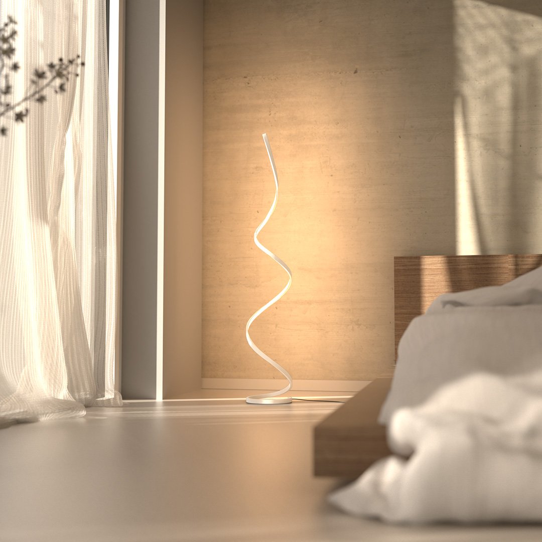 White LED spiral floor lamp beside a bed