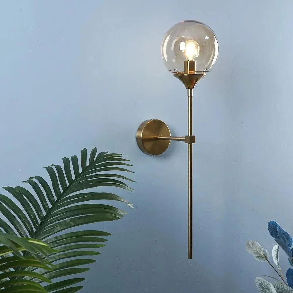 Clear globe brass wall light on a blue wall