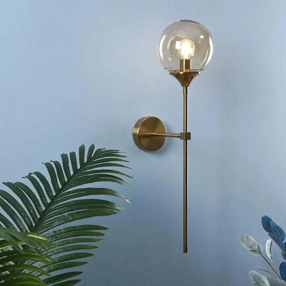 Clear globe brass wall light on a blue wall