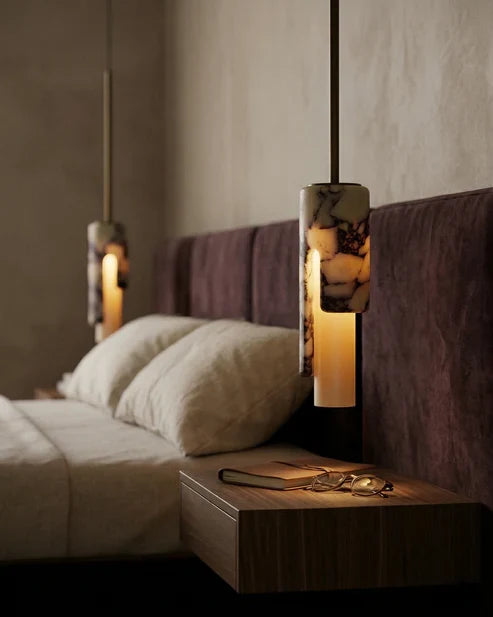 Cylinder pendant lights beside a bed