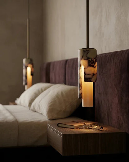 Cylinder pendant lights beside a bed