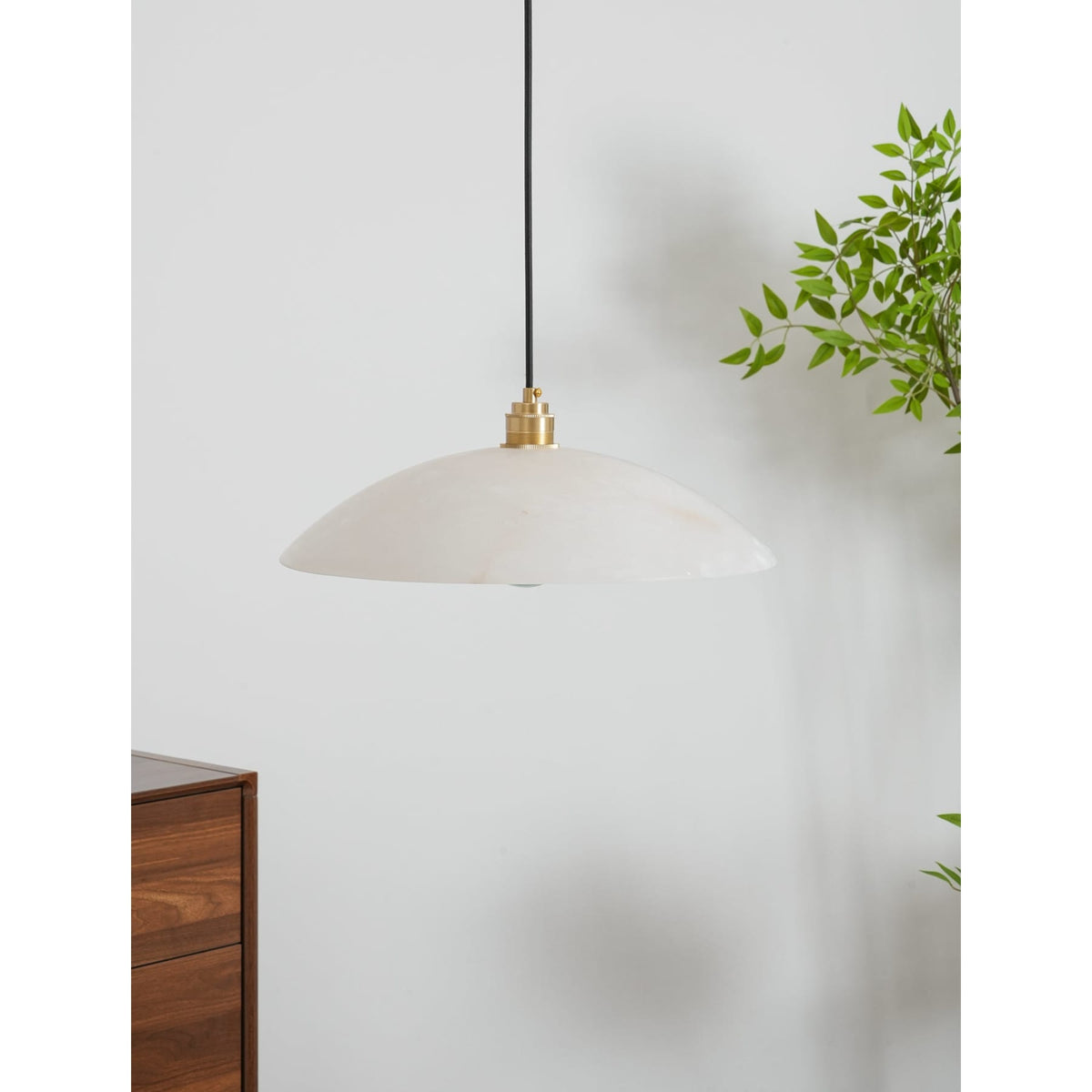 White marble shade suspended beside green foliage