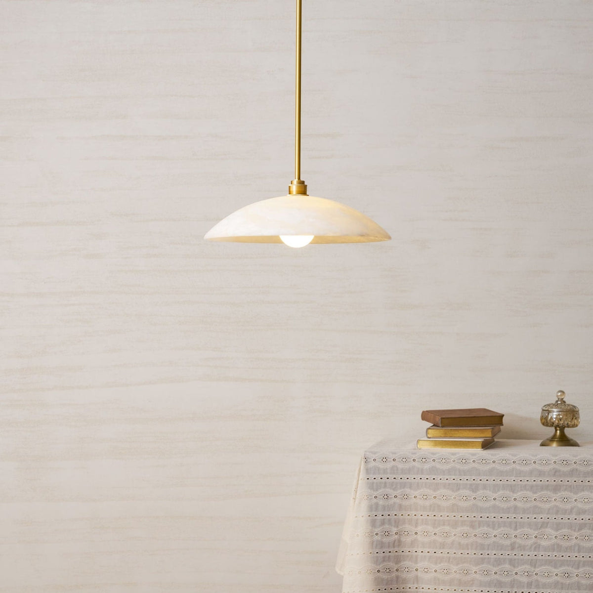 Warm light beneath a marble pendant on a metallic rod