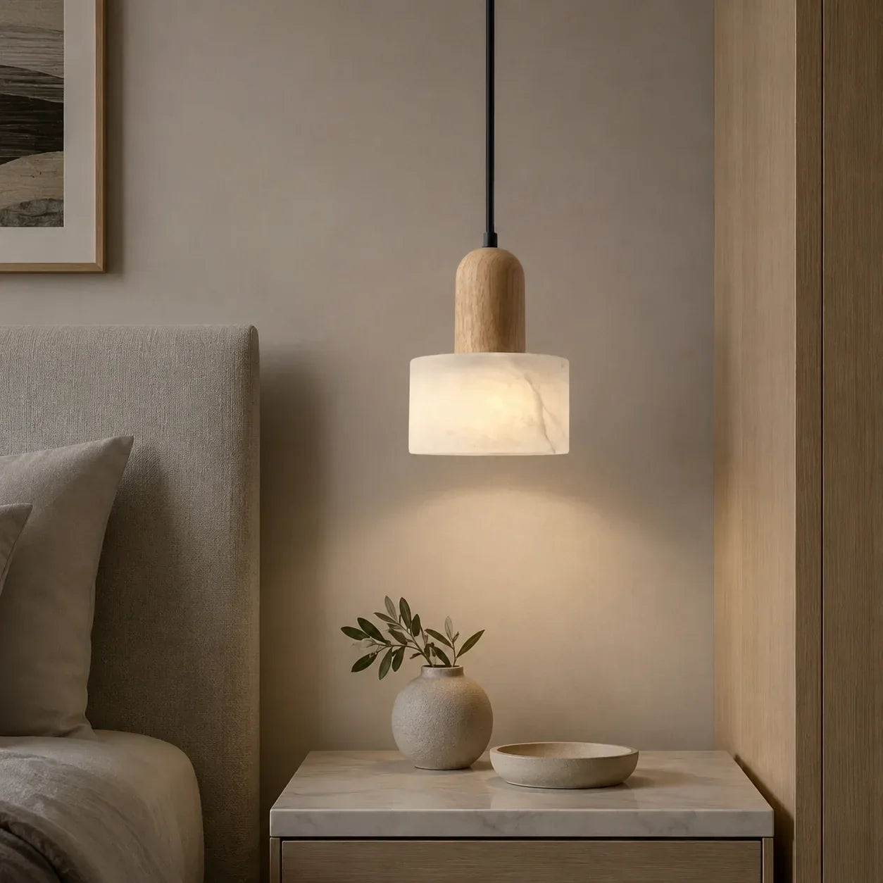 Minimalist pendant light featuring a cylindrical marble shade and natural wood detail, suspended above a bedside table in a serene, wabi-sabi bedroom.