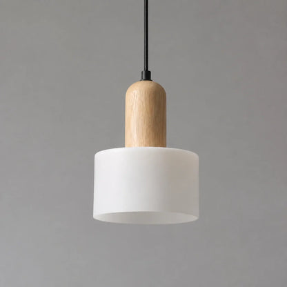 Minimalist pendant light featuring a cylindrical white marble shade with a natural wood top detail, suspended by a slim black cable against a grey backgrou
