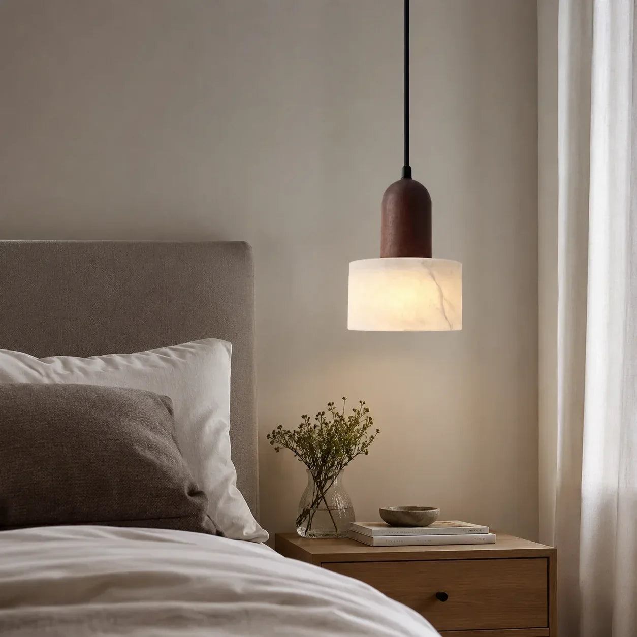 Minimalist pendant light featuring a cylindrical marble shade and dark wood top, hanging above a bedside table in a serene, neutral-toned bedroom.