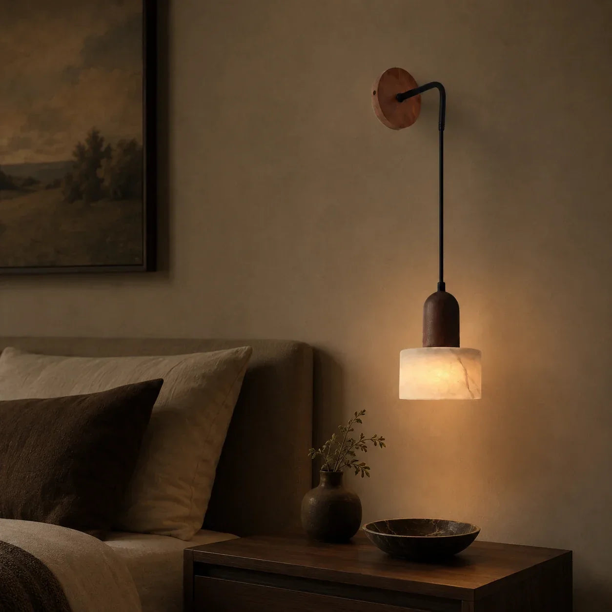 Minimalist wall-mounted pendant light with a walnut wood base and marble shade, emitting a warm glow above a bedside table in a cosy bedroom setting.