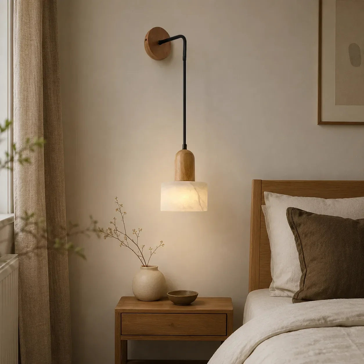 Minimalist wall-mounted pendant light featuring a natural wood fixture and marble shade, emitting a warm glow above a bedside table in a bedroom.