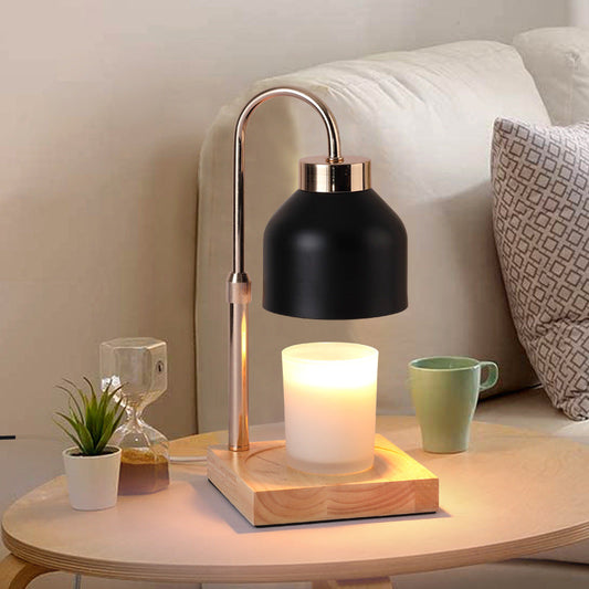 Black matte candle warmer lamp with a brass-style arm and solid wood base on a side table