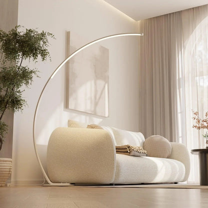White arc LED floor lamp extending over a sofa