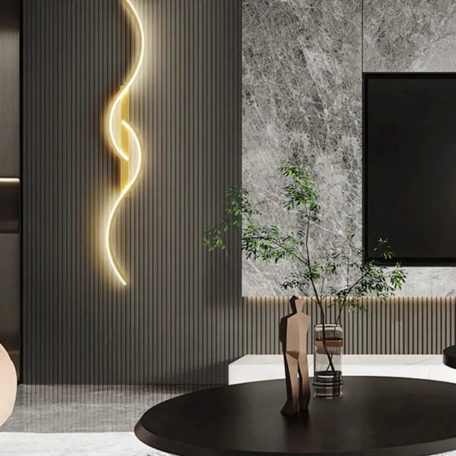 Minimalist curved LED wall light mounted on a dark slatted feature wall in a modern living room, casting a warm glow beside a marble panel and TV.