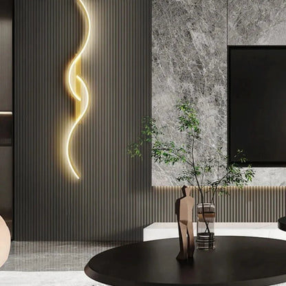 Minimalist curved LED wall light mounted on a dark slatted feature wall in a modern living room, casting a warm glow beside a marble panel and TV.