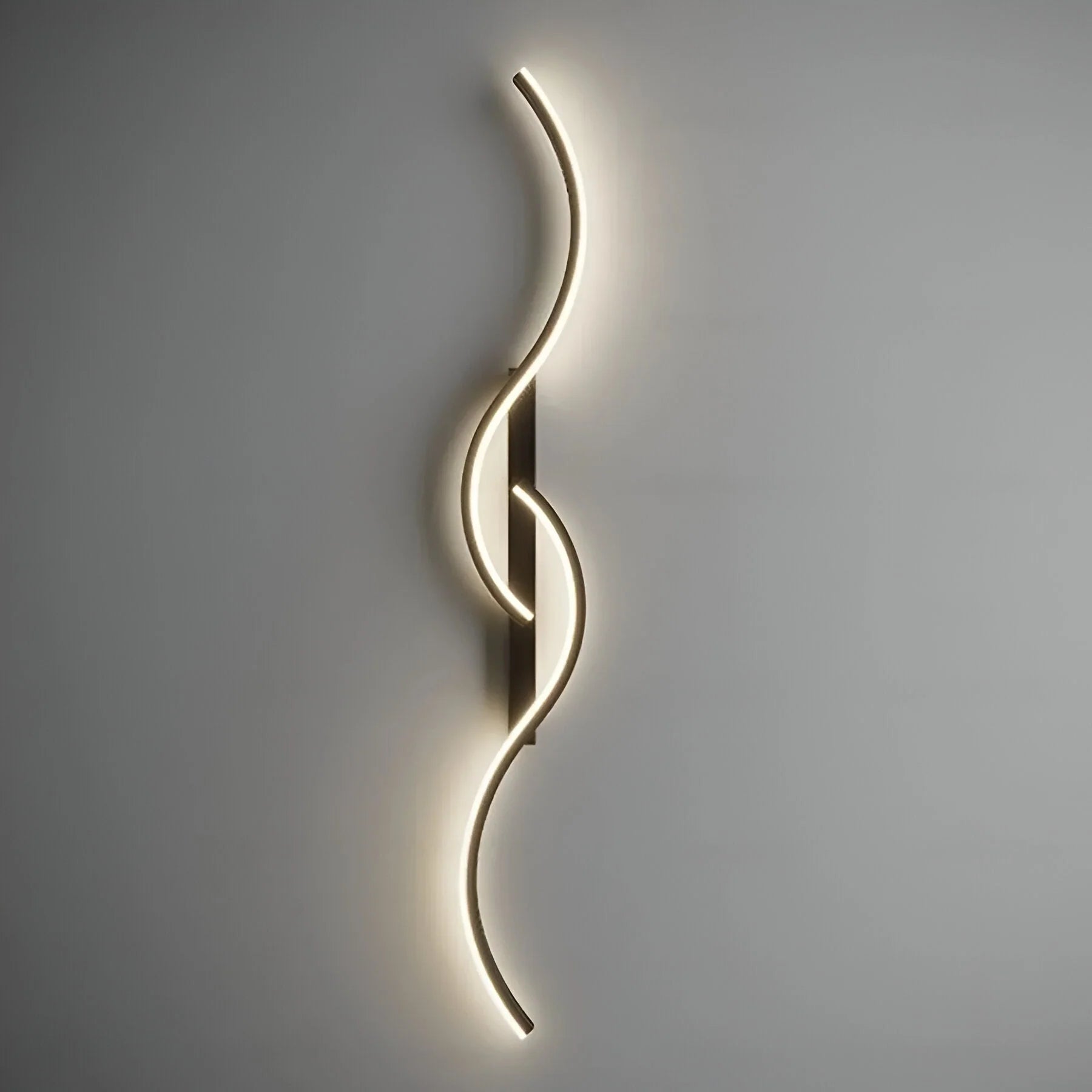 A minimalist curved LED wall light with a sleek, wave-like design mounted on a neutral grey wall, emitting a soft, warm glow for modern indoor lighting.