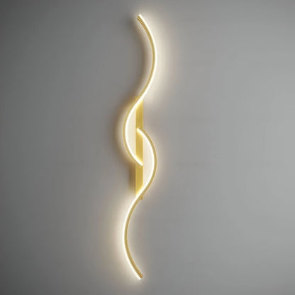 Minimalist gold curved LED wall light with a sleek wave design, mounted vertically on a grey wall and emitting a soft, warm glow for indoor lighting.