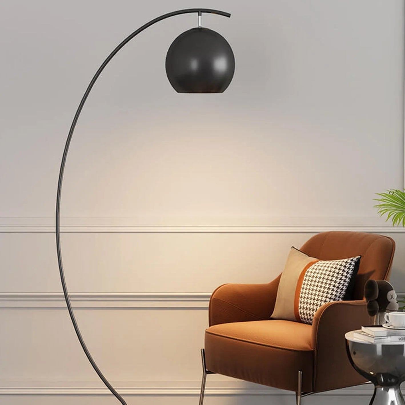 A minimalist black LED arc floor lamp with a spherical shade, positioned over a brown armchair in a modern living room setting.