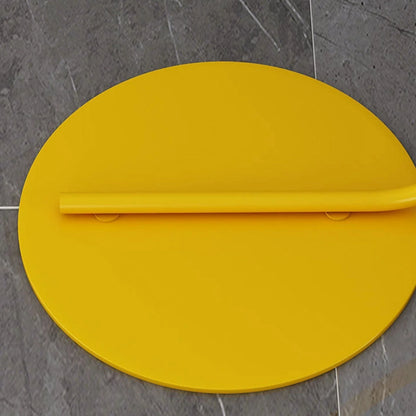 Close-up of the circular yellow metal base and lower stem of the minimalist LED arc floor lamp, resting on a grey tiled floor.