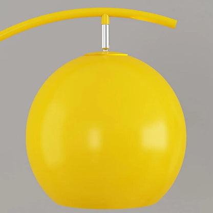 Close-up of the bright yellow spherical shade of a minimalist LED arc floor lamp, showing the adjustable silver connector and curved yellow arm.