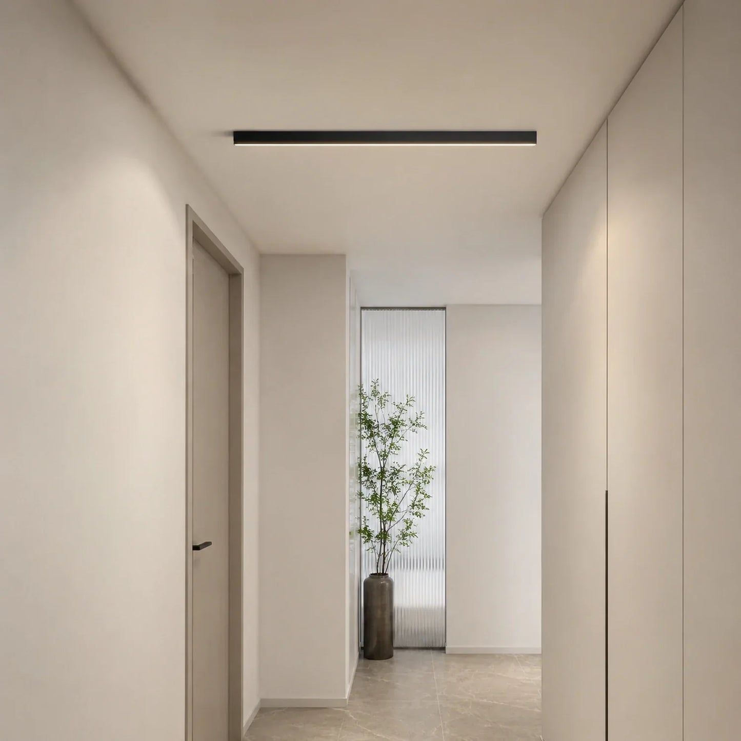 A sleek, black minimalist linear LED ceiling light installed in a modern hallway with neutral walls, light flooring, and a decorative potted plant.