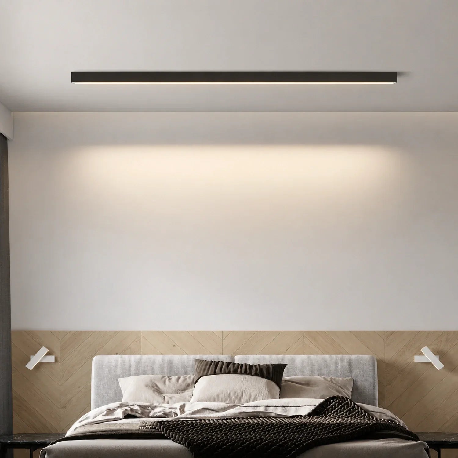 Minimalist black linear LED ceiling light mounted above a modern bedroom bed, casting a warm glow against the white wall and wooden headboard.